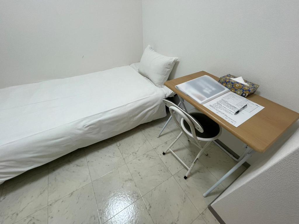 a small room with a bed and a desk with a laptop at A&C STAY Shin-Osaka83 in Osaka