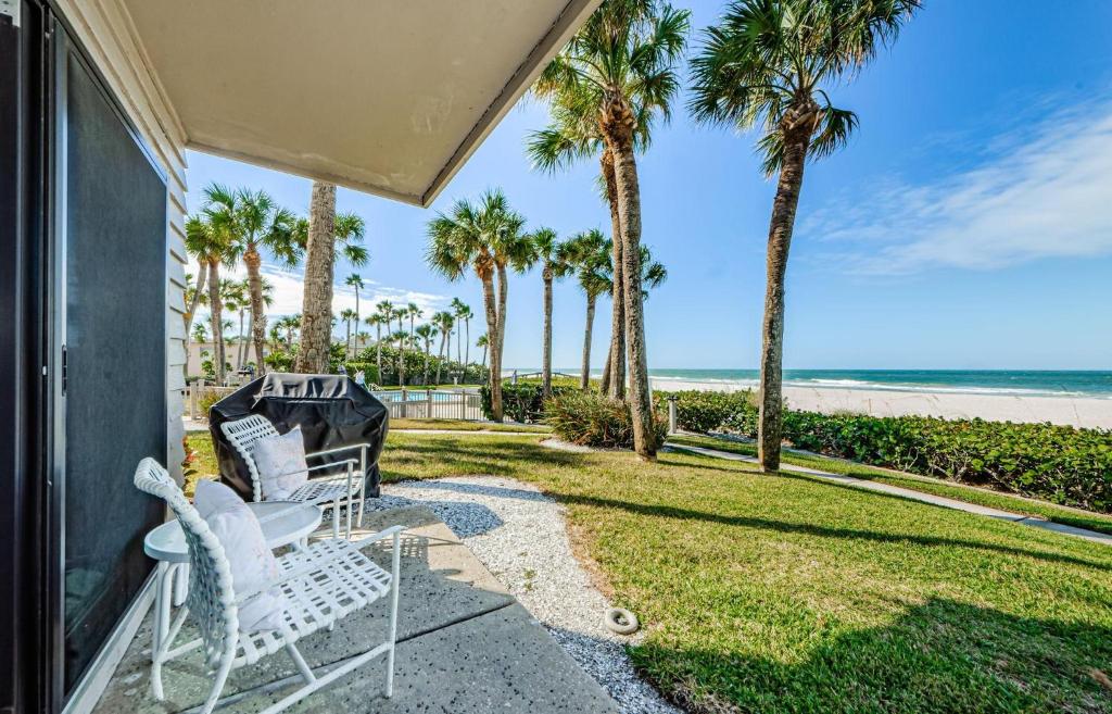 un porche con 2 sillas blancas y palmeras en Beachfront Aldea 11 en Clearwater Beach