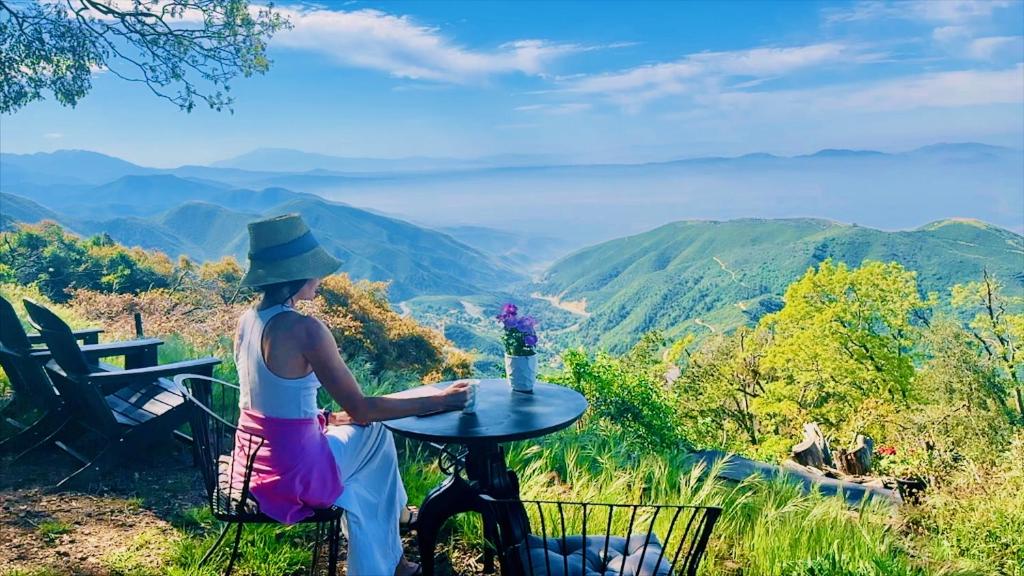 Crestline的住宿－100 Mile View-Fire Pit, Romantic, Peaceful, Private，坐在桌子上欣赏山景的女人