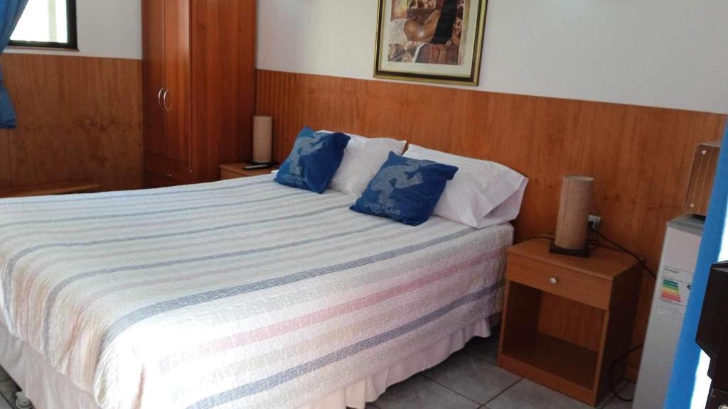 a bedroom with a large bed with blue pillows at Atavai Hotel Rapa Nui in Hanga Roa