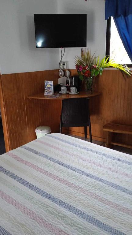 a bedroom with a bed and a table with a television at Atavai Hotel Rapa Nui in Hanga Roa