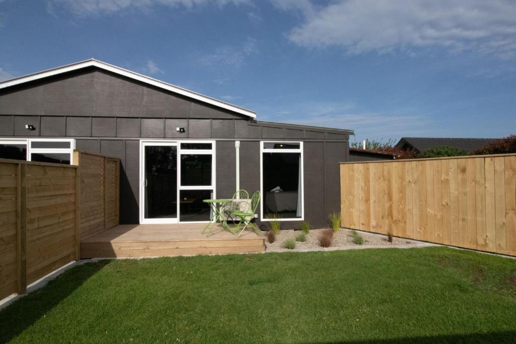 a gray house with a lawn in front of it at The Flight Pad Aisle Seat Pet Friendly in Waitara