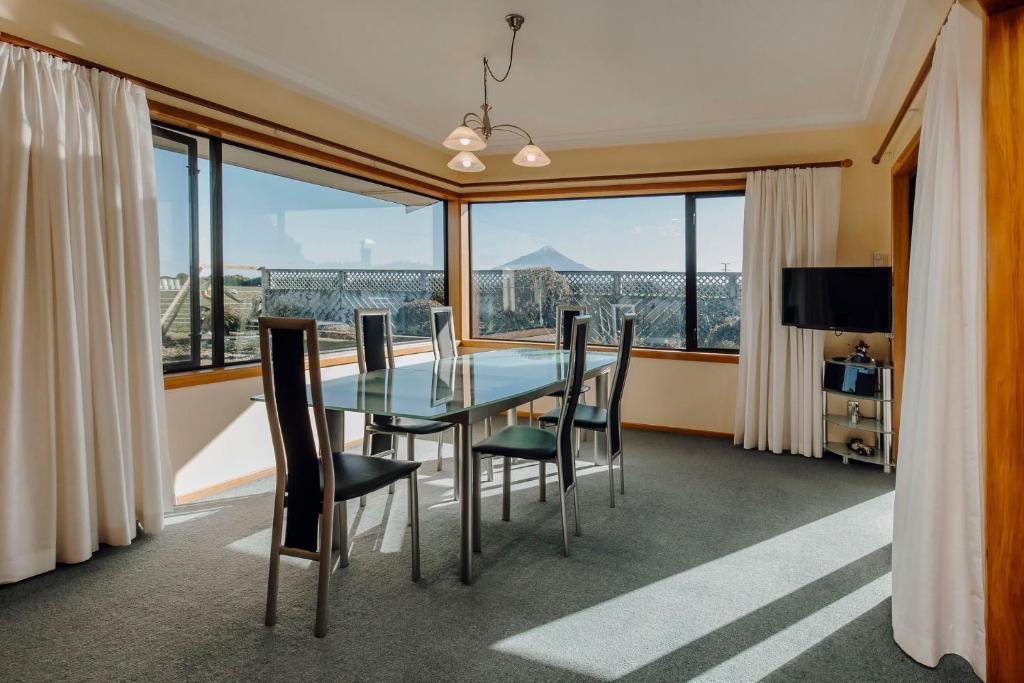 a dining room with a table and chairs and a large window at Mt Taranaki Vista 