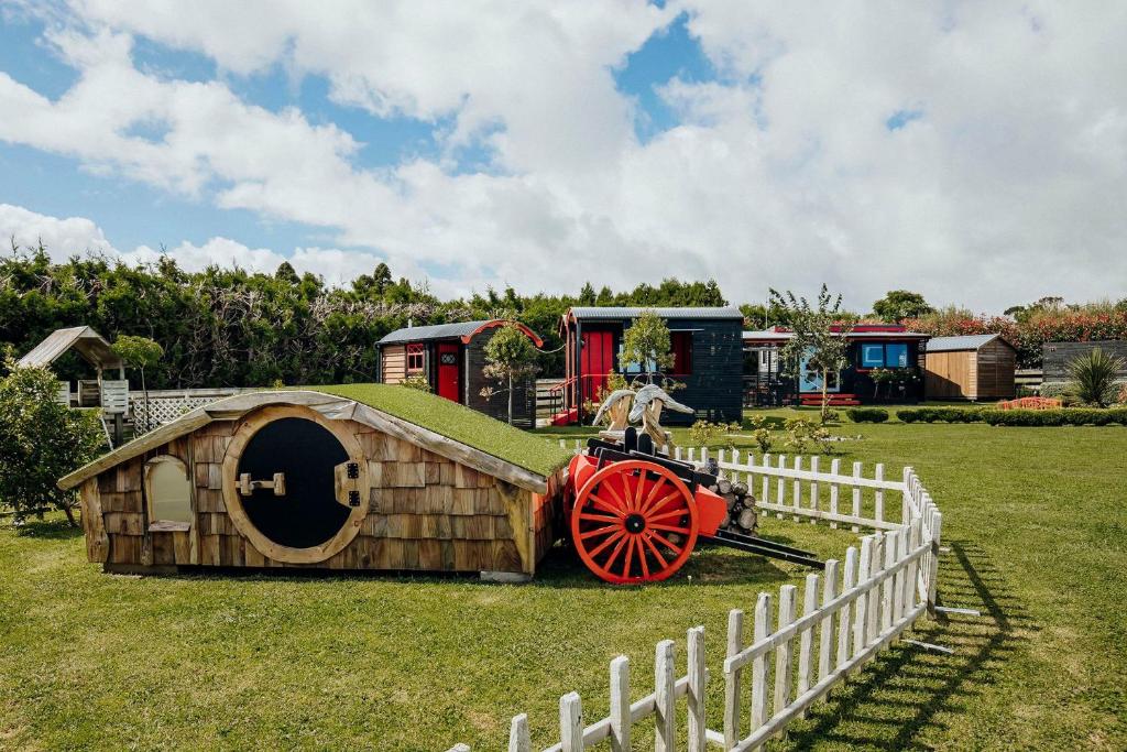 a small house with a tractor in a field at Onaero s Quaint Little Cottages in Waitara