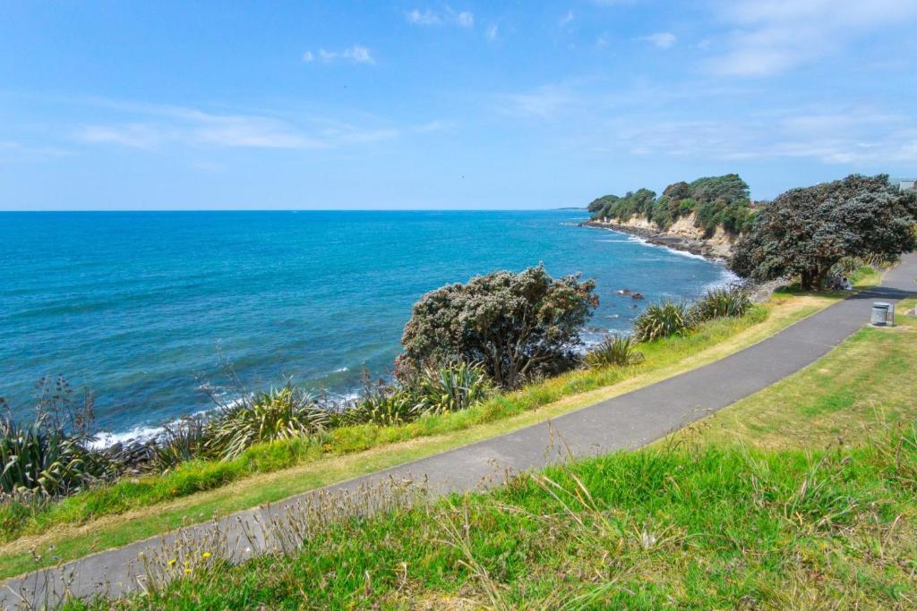 a road next to the ocean on a sunny day at Mountain View Ark Apartment in New Plymouth