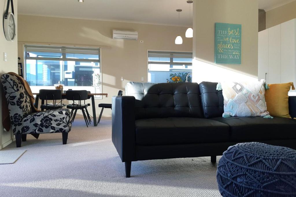 a living room with a black couch and a chair at Escape To Buller Prime Holiday Location in New Plymouth