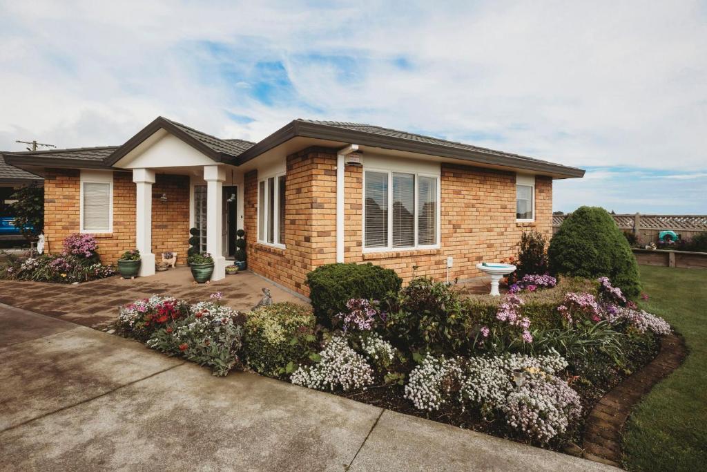 a brick house with flowers in the front yard at Stay At Saddle Row in New Plymouth
