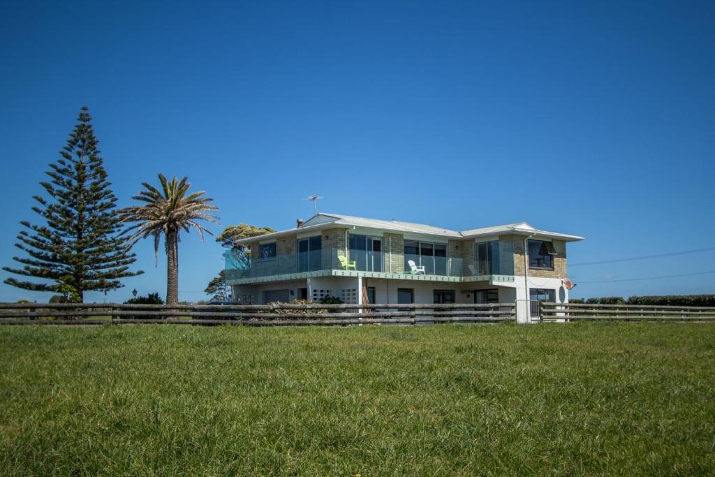 a large house with a palm tree in a field at Wills On The Water Beachfront Apartment in Bell Block