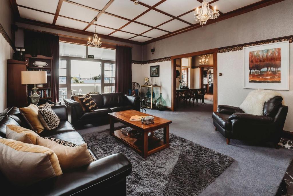 a living room with leather couches and a coffee table at Timata Ora Sleeps 14 in New Plymouth