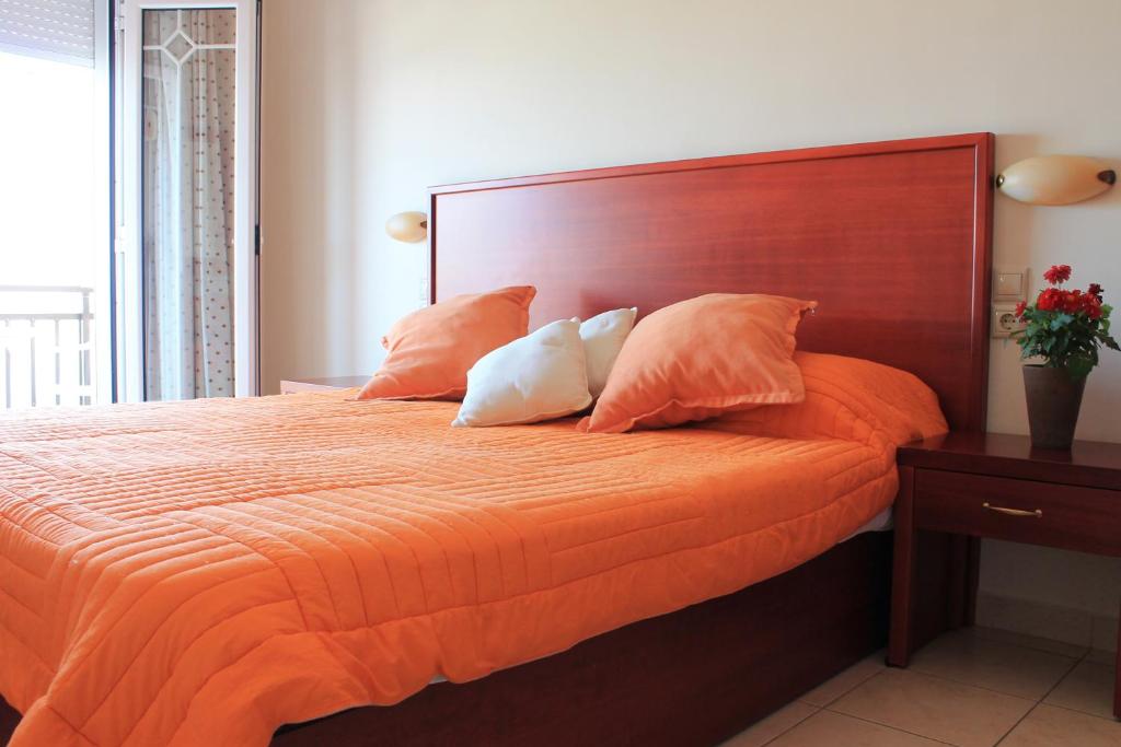 1 cama grande con sábanas y almohadas de color naranja en Xaris, en Platamonas