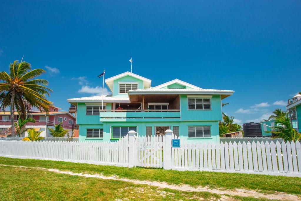 ein blaues Haus hinter einem weißen Zaun in der Unterkunft Casa Al Mar, St. George's Caye - Belize in Belize City