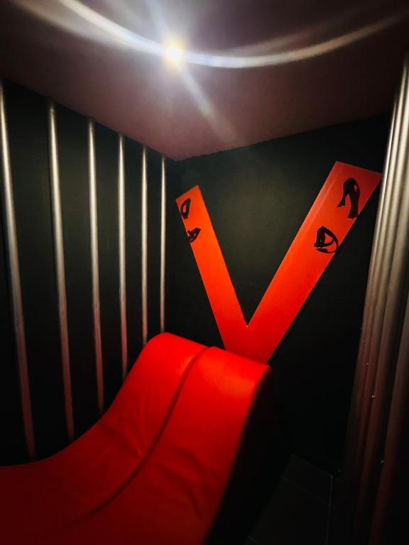 a red chair with a letter v on a wall at Ya no tenemos servicio in Mexico City