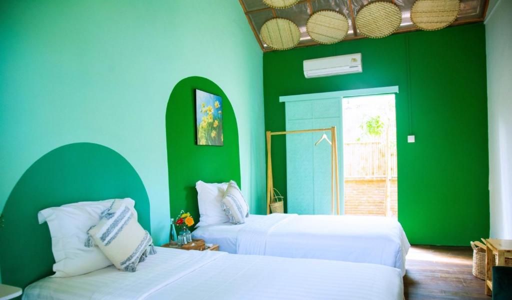 two beds in a room with green and blue walls at Lumiere Family Village Dong Tac in Hiếu Xương