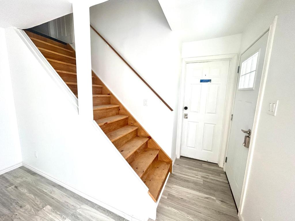 - un escalier dans une maison dotée de murs blancs et de parquet dans l'établissement Aubin Paradise Housing, à Windsor