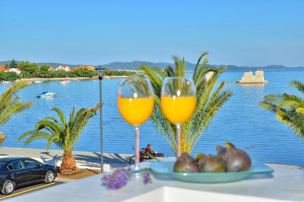 a table with two glasses of orange juice and a plate of fruit at Design Apartments Dijan in Sukošan