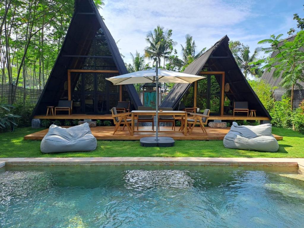 Kejayan的住宿－Villa Verde the garden，游泳池畔带桌子和遮阳伞的帐篷