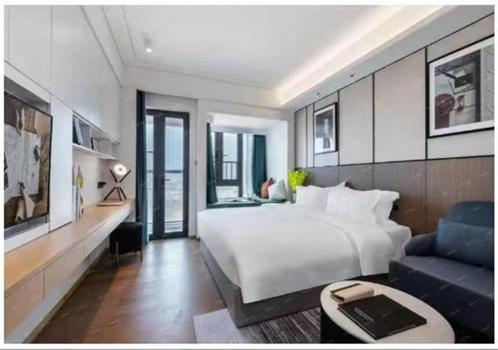 een slaapkamer met een groot bed en een blauwe bank bij Royal Executive Apartment, Shenzhen World Exhibition & Convention Center, Nearby Shenzhen World North Metro St ation in Bao'an