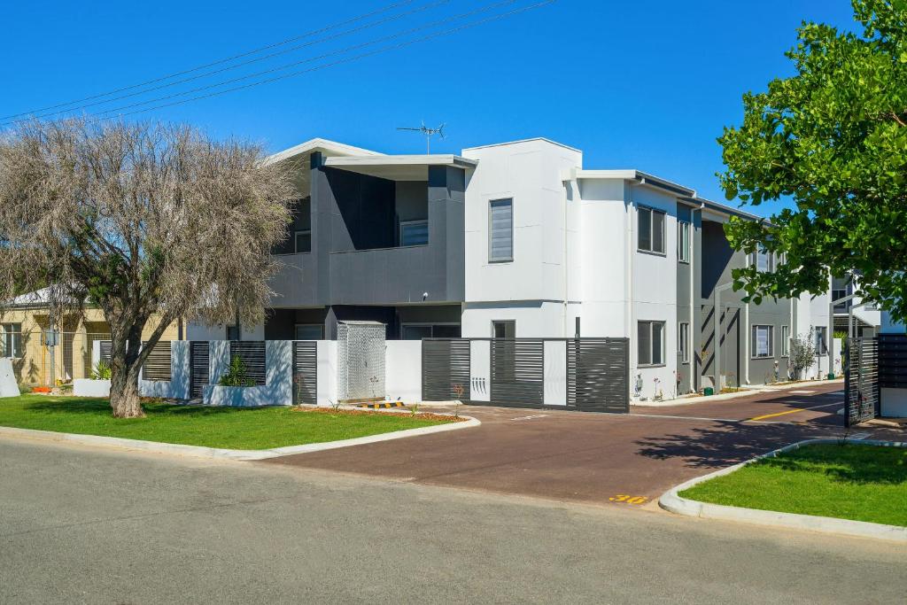 a white building on a street with a tree at Hillside Merrifield Suites in Kelmscott