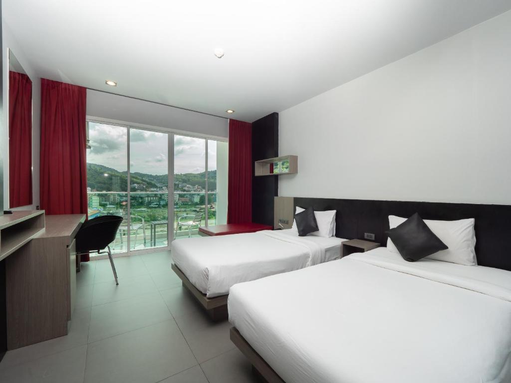 ein Hotelzimmer mit zwei Betten und einem Fenster in der Unterkunft Neon Patong in Patong Beach