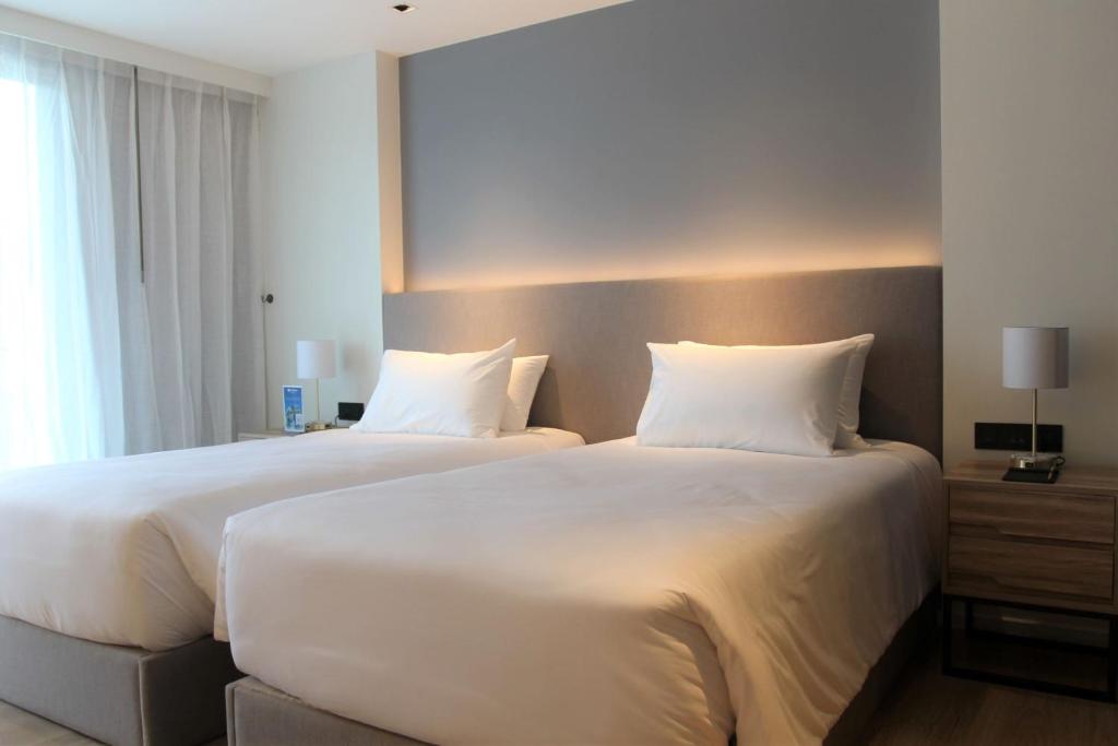 two beds in a hotel room with white pillows at Wyndham La Vita Rawai Phuket in Rawai Beach