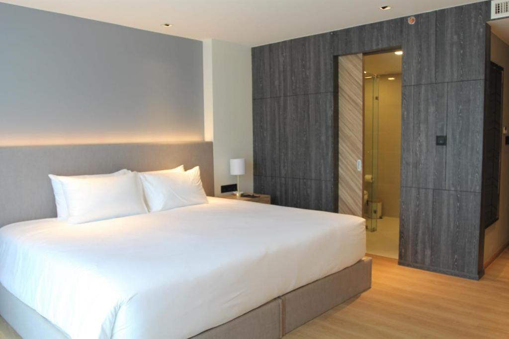 a bedroom with a large white bed and a door at Wyndham La Vita Rawai Phuket in Rawai Beach