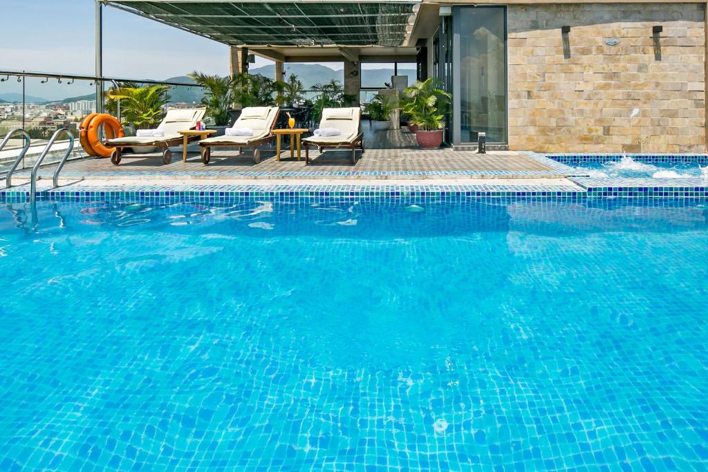 een groot blauw zwembad met stoelen en een tafel bij Bliss Luxury Hotel & Spa in Da Nang