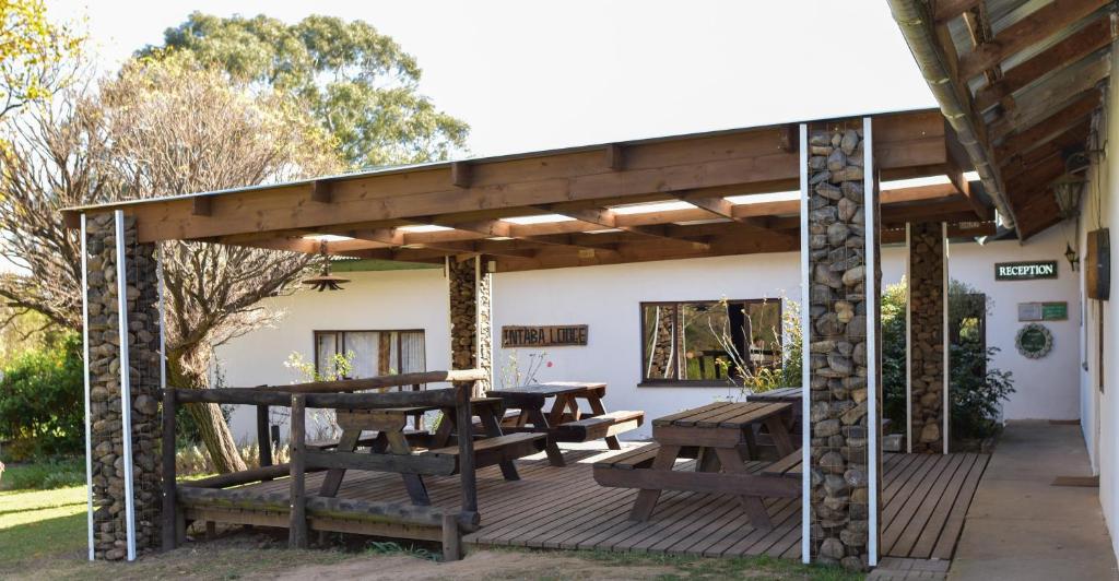 pergolato in legno con tavoli da picnic e panche su una terrazza di Intaba Lodge a Elliot