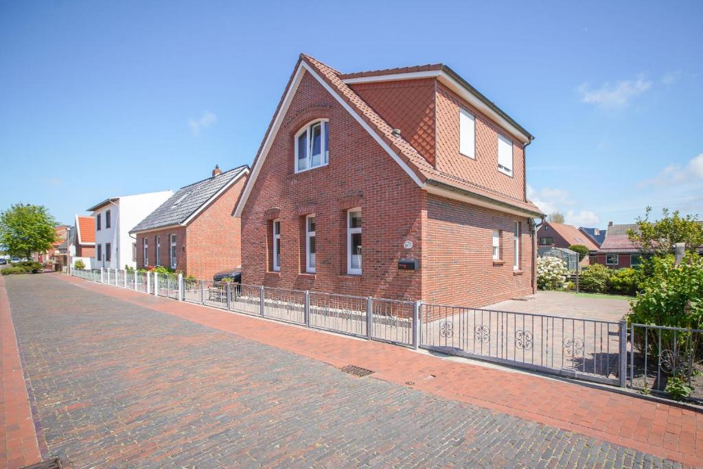 a red brick house with a fence on a street at Ferienhaus Daheim in Borkum