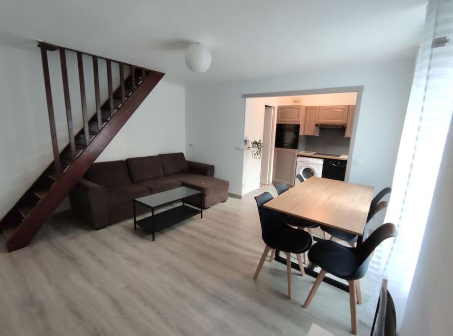 un soggiorno con un tavolo e un divano di Duplex Cosy a Gonesse