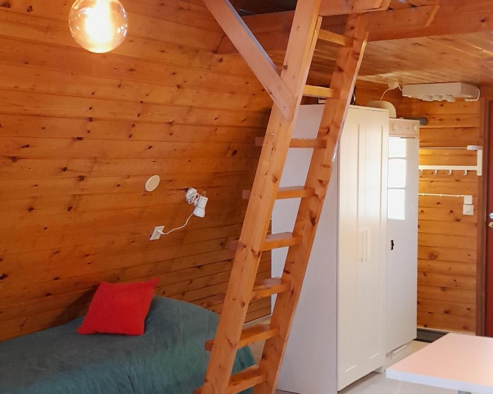 a bedroom in a log cabin with a ladder at Karemajat Cottage Resort in Ylitornio