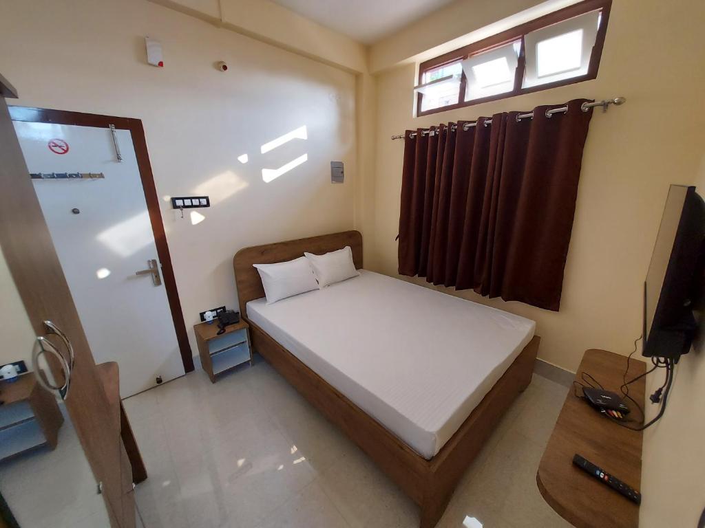 a small bedroom with a bed and a television at Hotel Hari Gayatri Regent in Guwahati
