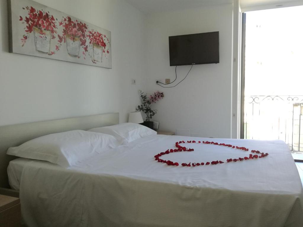 マテーラにあるLa Scala Suiteの白いベッド(赤いハートの装飾付)