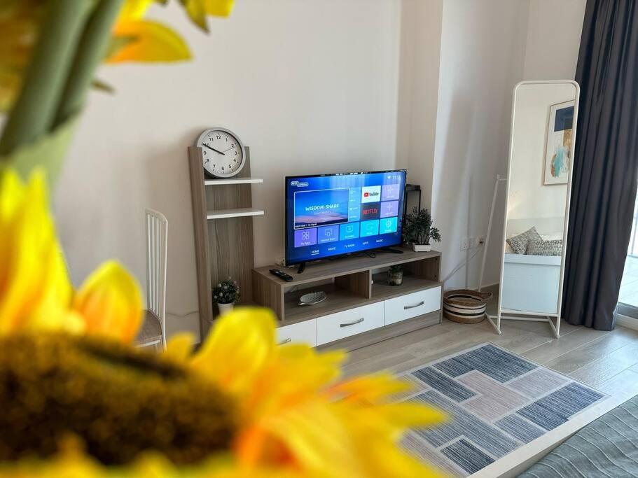 sala de estar con TV y reloj en la pared en Comfy is just a holiday home! 105WB2, en Abu Dabi
