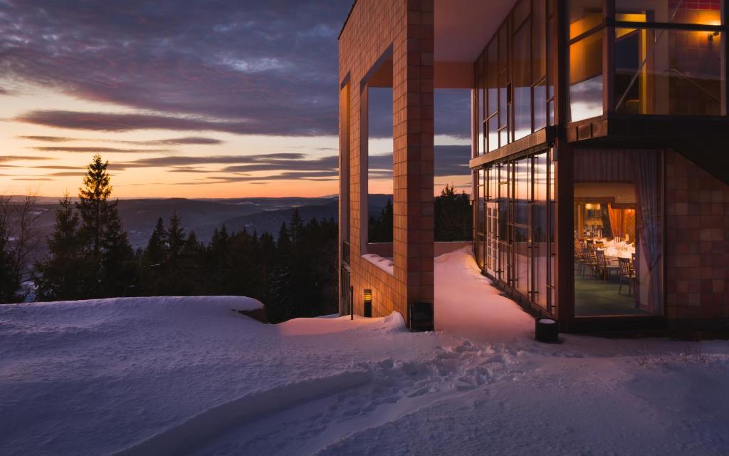 a building in the snow with the sunset in the background at Soria Moria Hotell in Oslo