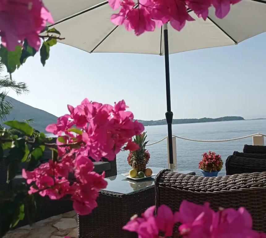 einen Tisch mit rosa Blumen und einem Regenschirm in der Unterkunft Villa Leonardo in Mlini