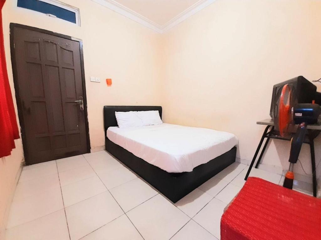 a bedroom with a bed and a tv in it at SPOT ON 93326 Pondok Anie Syariah in Pekanbaru