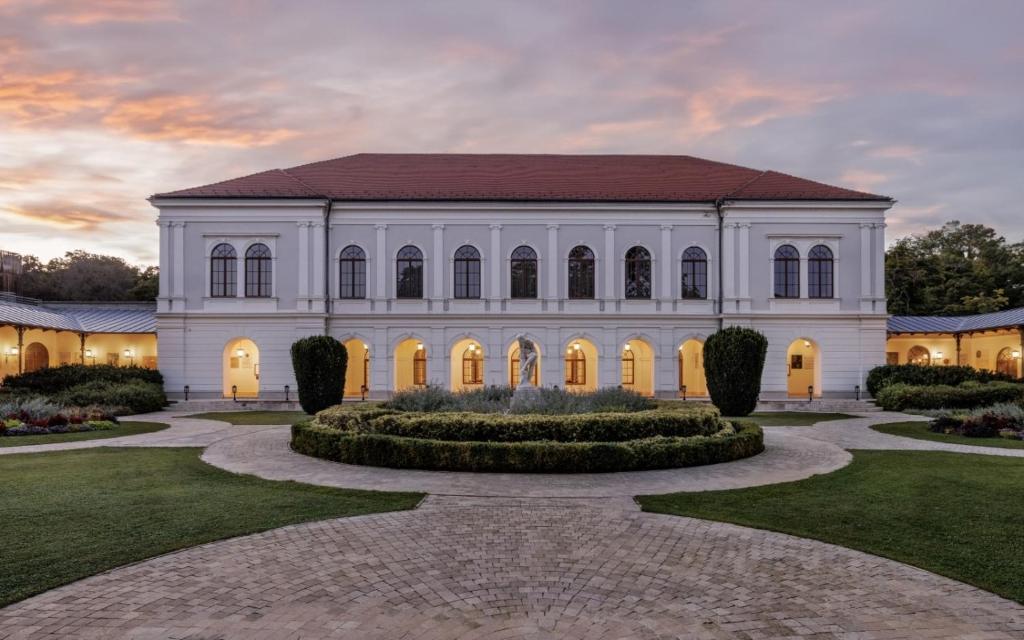 a large white building with a garden in front at Anna Grand Hotel in Balatonfüred