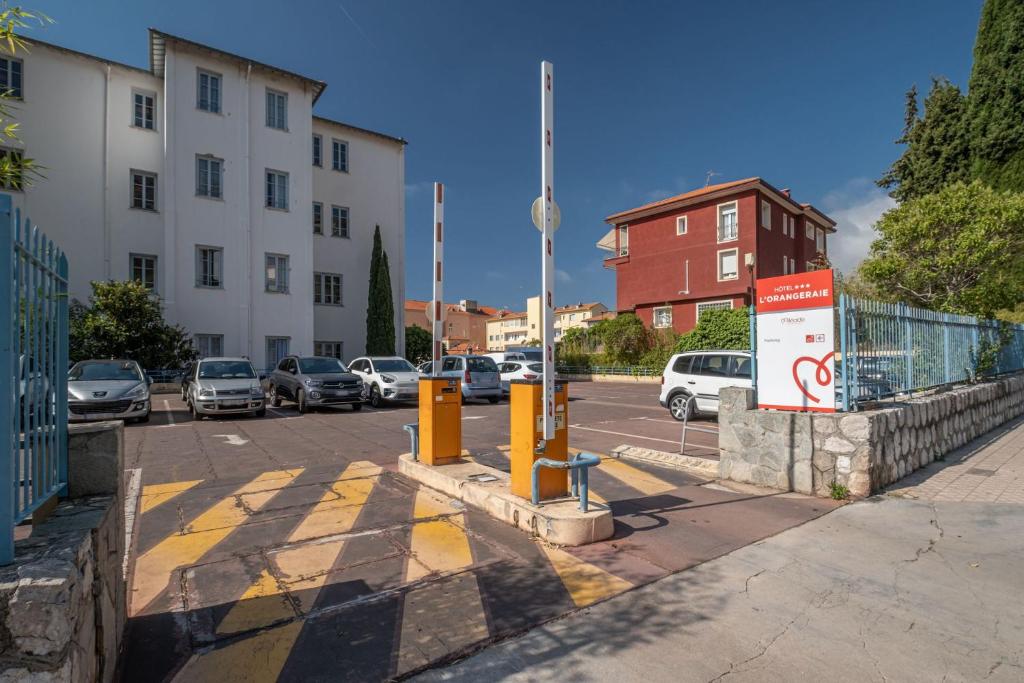 a street with cars parked in a parking lot at Hôtel Miléade L'Orangeraie - Menton in Menton