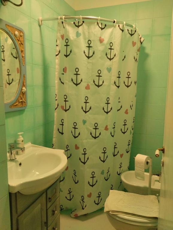 uma casa de banho com um lavatório e uma cortina de chuveiro com uma âncora em Casa Alma monolocale per 2 persone em Porto Ercole