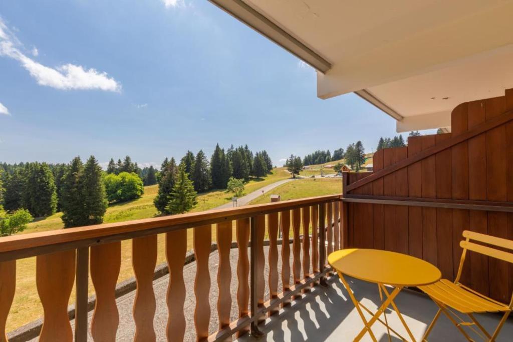 a balcony with a yellow chair and a view of a field at Chaleureux studio au pied des pistes - Le refuge in Les Déserts