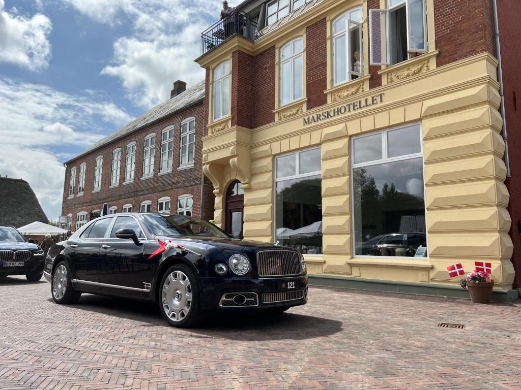 ein schwarzes Auto, das vor einem Gebäude parkt in der Unterkunft Marsk Hotellet in Højer