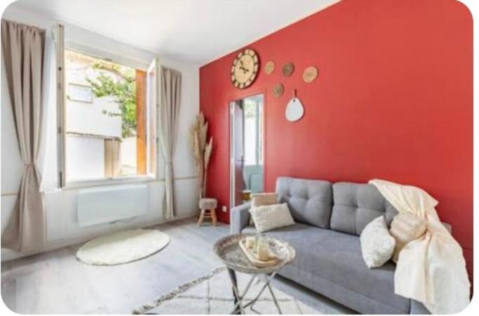 a living room with a gray couch and red wall at Maison cosy Paris Orly jardin privée in Vitry-sur-Seine