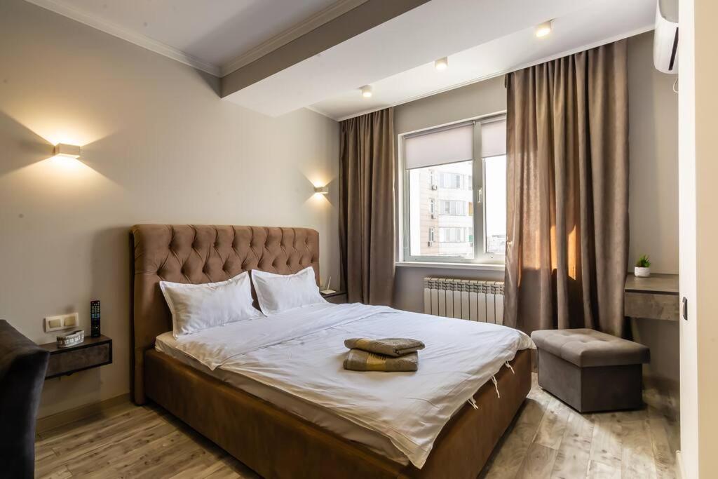 Un dormitorio con una cama grande y una ventana en Apartments in the Golden square 141, en Almaty