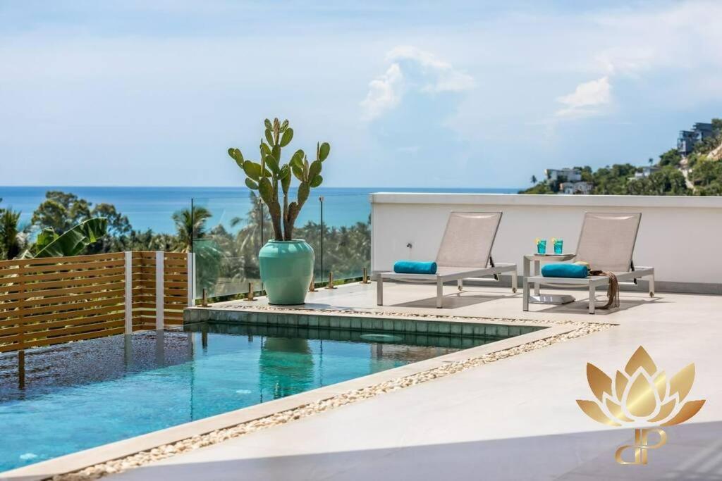 una piscina con due sedie e un tavolo e l'oceano di Luxury Villa - Chaweng Noi Seaview - 6 bedroom - Gym et cinema room a Nathon Bay