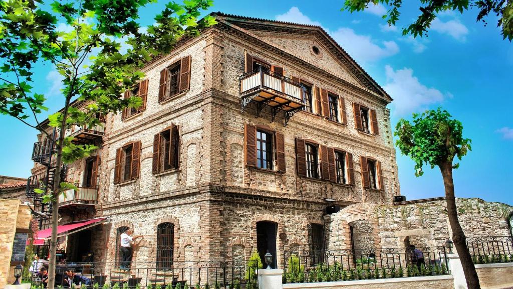 un antiguo edificio de piedra con balcón. en Giritligil Hotel, en Manisa