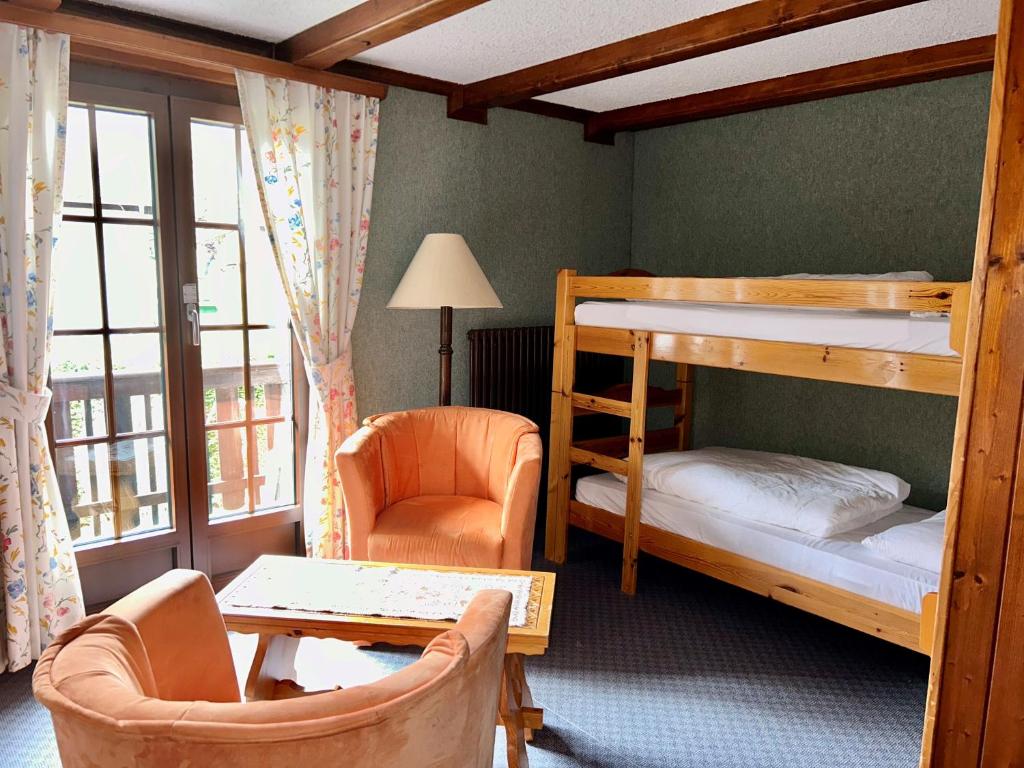 a bedroom with bunk beds and a desk and a chair at B & B Hôtel Aux Mille Etoiles in Les Marécottes