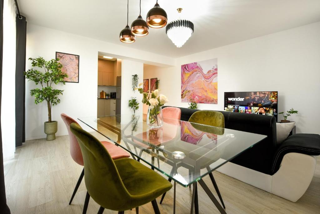 una sala da pranzo con tavolo in vetro e sedie verdi di Urban Bliss - Contemporary Elegance in Modern Living Spaces a Voluntari
