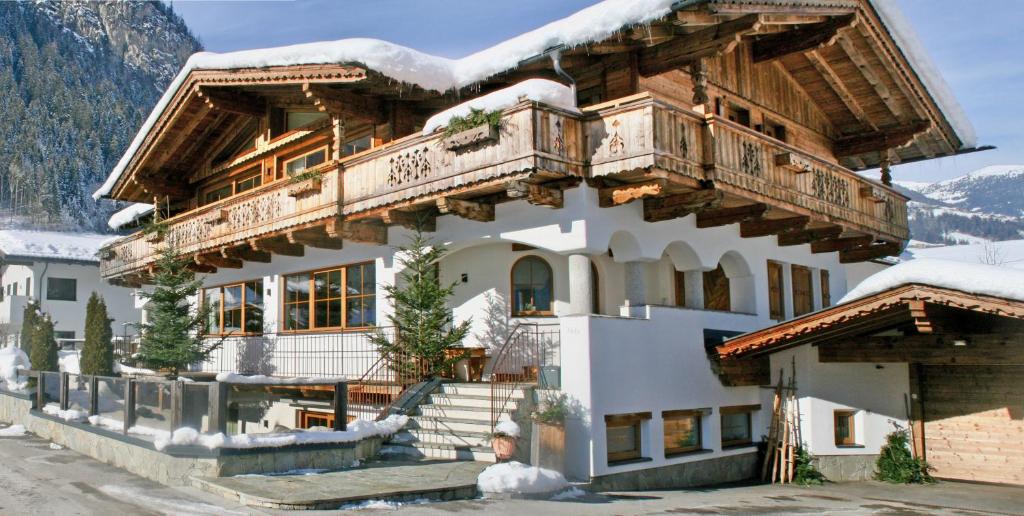 a house in the mountains with snow on it at Appartements "Da Zillertaler und die Geigerin" in Mayrhofen