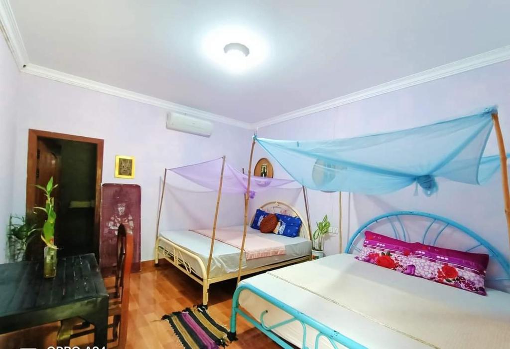 a bedroom with two beds with a canopy at Phonluer Angkor Homestay, in Siem Reap
