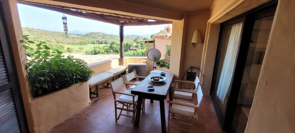 a balcony with a table and a bench and a window at Cava di Volpe , Case Del Golf Pevero, Costa Smeralda in Abbiadori